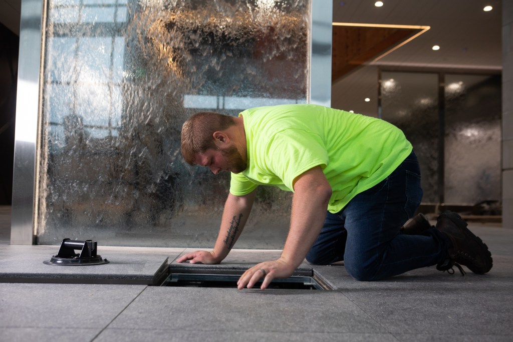 Man in a high vis t-shirt looking under a floor panel